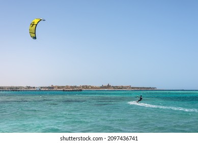 Hurghada, Egypt - June 02, 2021: Kite Surfing Man With Kite In Sky On Board In Sea Riding Waves In Makadi Bay, Which One Of Egypt Beautiful Red Sea Riviera. Kiteboarding Sport.