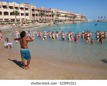  Hurghada, Egypt, November 15, 2012: Animation At Resort Hotel SUNNY DAYS El PALACIO 5 Star. Tanned Man  Suit Conducts Classes For Tourists In Water Aerobics In Sea