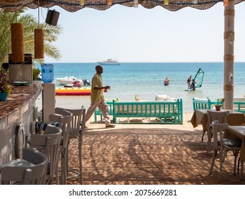 Hurghada, Egypt - September 22, 2021: View of the bar on the beach of the red sea. The bartender carries drinks to the resting people sitting at the table.