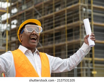 Hurrah, Exulting And Joyful Indian Engineer Holding Rolled Up Plans On Construction Site