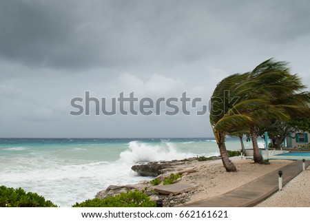 A hurricane is about to batter this caribbean beach hut. The seas are raging and the skies show the tropical storm as the power of nature is demonstrated. Waves crash on the shore