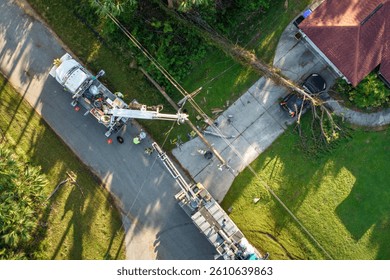 Hurricane aftermath in Florida. Workers using bucket trucks to repair blown down electrical wires at residential house. Utility services fixing damaged power lines