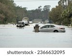 Hurricane flooded street with broken car in surrounded with water Florida residential area. Consequences of natural disaster