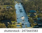 Hurricane flooded street with moving cars and surrounded with water houses in Florida residential area. Consequences of natural disaster