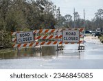 Hurricane flooded street with road closed signs blocking driving of cars. Safety of transportation during natural disaster concept