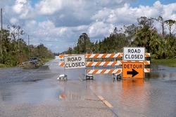 Hurricane Flooded Street With Road Closed Signs Blocking Driving Of Cars. Safety Of Transportation During Natural Disaster Concept