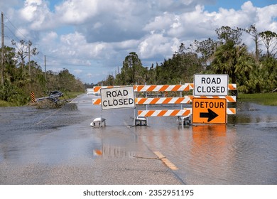 Hurricane flooded street with road closed signs blocking driving of cars. Safety of transportation during natural disaster concept
