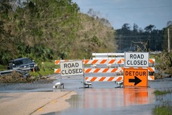 Hurricane Ian Flooded Street With Road Closed Signs Blocking Driving Of Cars. Safety Of Transportation During Natural Disaster Concept