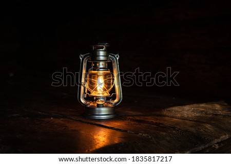 Hurricane Lantern Lighting up the Dark on a Wooden Table and with a Dark Background, Warm Reflecting light