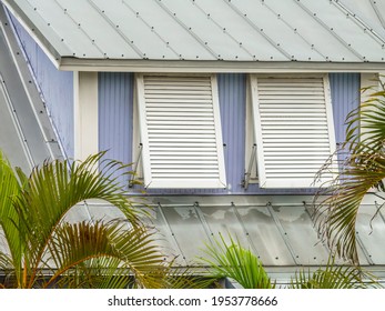 Hurricane Shutters, Slightly Weathered, On Two Windows Of A Small Building With Tin Roofing In A Beach Town On A Barrier Island Along The Gulf Coast Of West Central Florida