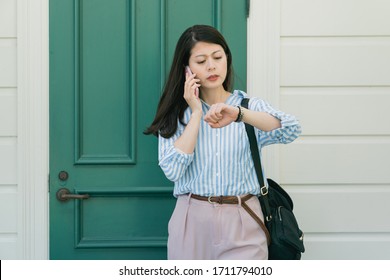 Hurry Up! Portrait Of Responsible Attractive Asian Woman Having Important Call Speaking By Smart Phone Looking At Luxury Watch On Wrist. Frowning Young Girl Talking On Cellphone Telling To Be Quick