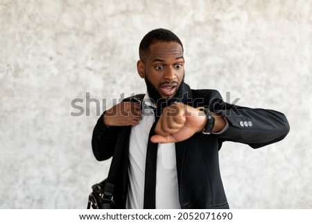 Hurry Up To Work. Portrait of shocked worried black business man with open mouth looking at wrist watch, African American male wearing suit scared of being late to meeting, rushing to office workplace