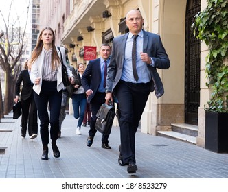 Hurrying Business People With Stressed Man In Foreground Running On City Street..