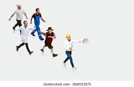 Hurrying Specialists. Group Of Young Men Of Different Professions Running Isolated On White Background. Male Models In Image Of Waiter, Mechanic, Cook, Chemist And Architect. Flyer With Copy Space For