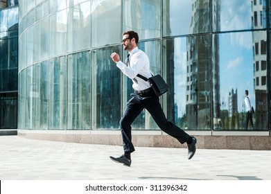 Hurrying To Work. Full Length Of Young Businessman Looking Forward While Running Along The Street