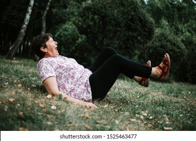 Hurt Senior Woman Felt On The Ground On Her Back With Both Legs In The Air Outdoors - Cute Old Lady Injured In The Grass After Slipping Off Her Feet In The Park - Weak Elderly Person Suffering