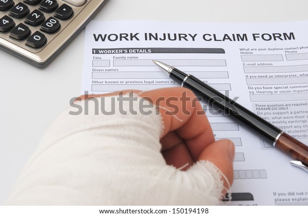 hurted hand and work injury claim\
form with pen & calculator, medical and insurance\
concept