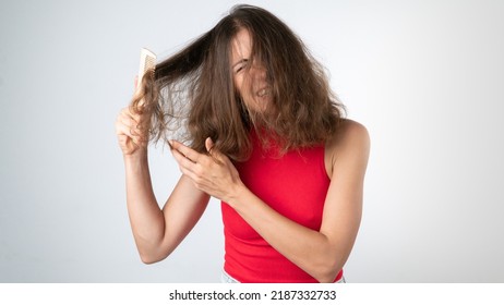 It hurts a woman when combing naughty, tangled hair - pulling out a comb and pulling her hair. High quality photo