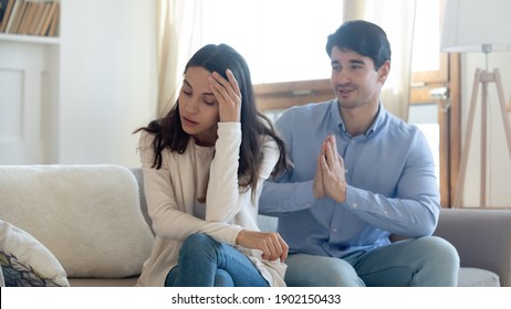 Husband asking forgiveness, making peace with offended annoyed wife after quarrel or cheating, young woman ignoring man, not talking, family crisis, relationship problem, break up and divorce - Powered by Shutterstock