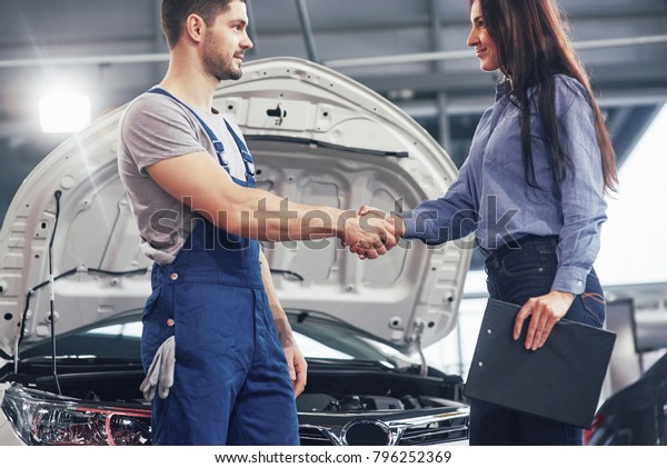 husband car mechanic and woman customer make an\
agreement on the repair of the\
car.