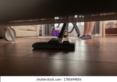 Husband Cleaning Dust Under Sofa With Vacuum Cleaner.