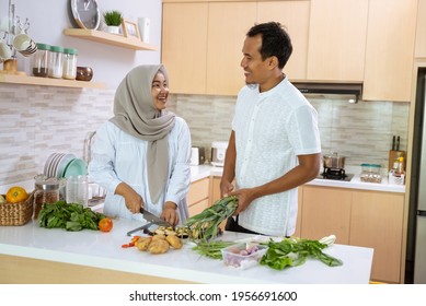 Husband Help His Wife In The Kitchen. Muslim Asian Couple Preparing Dinner Together. Romantic Young Man And Woman Have Fun Making Food At Home