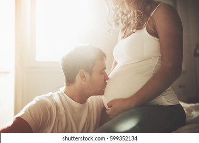 Husband Kissing  Newborn Through Wife Belly