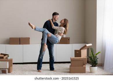 Husband lifts wife on arms, happy homeowner family celebrate relocation day in unfurnished living room with heap of carton boxes. Moving to new own or rented home, bought first dwelling. Loan concept - Shutterstock ID 2025161525
