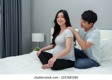 husband massaging shoulders of his pregnant wife on a bed. she suffering from back pain