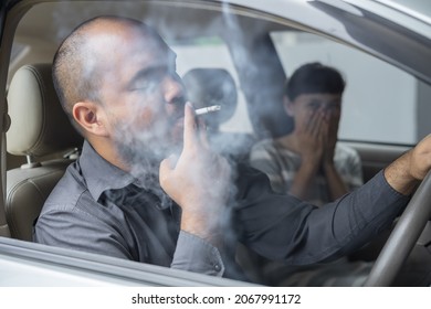 Husband smoking cigarette and wife choking of smoke. Man smoking cigarette and woman is covering her face and a lot of smoke around in car smelling pollution. Passive stop smoking cigarettes campaign.