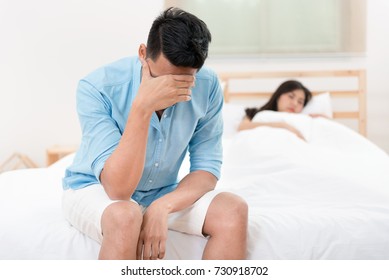 Husband unhappy and disappointed in the erectile dysfunction during sex while his wife sleeping on the bed. Sexual Problems in Men. 