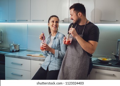 Husband and wife having fun with smoothie in the kitchen and looking at each other - Powered by Shutterstock