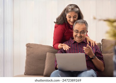 A HUSBAND AND WIFE LOOKING AT LAPTOP IN SURPRISE - Powered by Shutterstock