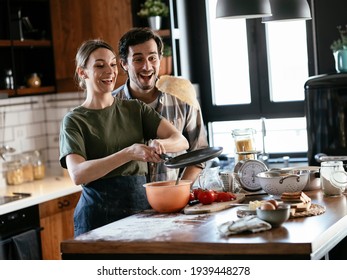 Husband and wife making pancakes at home. Loving couple having fun while cooking. - Powered by Shutterstock