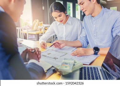 Husband And Wife Sign The Loan Agreement For Home Purchase To The Bank Officer.