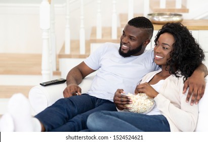 Husband And Wife Sitting On Couch With Popcorn, Watching Tv At Home, Side View