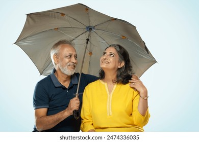 HUSBAND AND WIFE SITTING TOGETHER UNDER AN UMBRELLA
 - Powered by Shutterstock