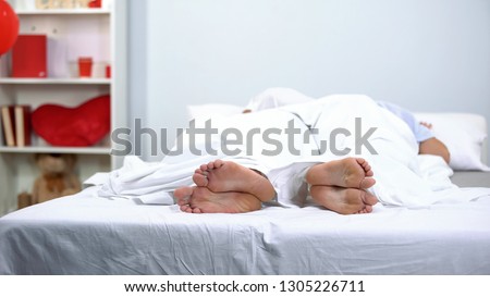 Husband and wife sleeping in bed, healthy feet seen under blanket, antifungals