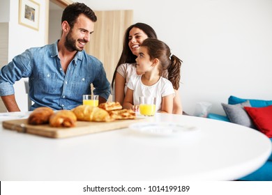 Husband and wife with they little daughter sitting at the kitchen table.Family portrait. - Powered by Shutterstock