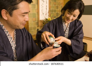 husband and wife in yukata pouring out alcohol drink