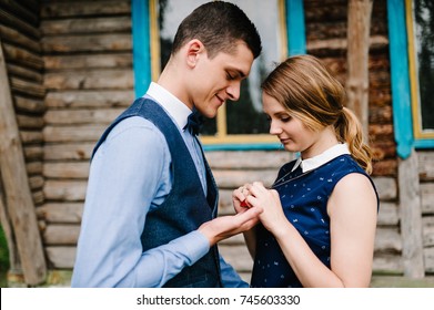 Husband's And Woman Hands Hold Heart Necklace Hanging Around His Neck Near Breast Against The Backdrop Of A Wooden Wall Of The House. Close Up. Love. Upper Half Length. Necklace.