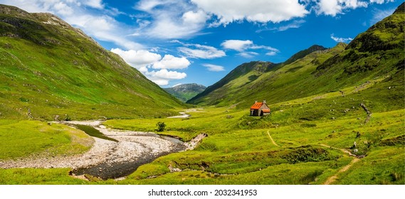 A hut in a mountain valley. Mountain cabin in mountain valley. Mountain panoramic landscape