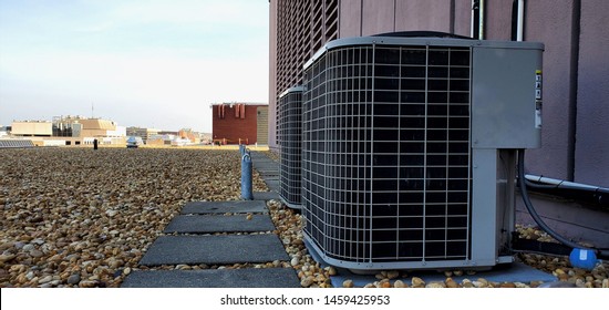 HVAC AC Compressor Coil Outside Installation With Fan And Radiator And Protective Mech. Installed Coil On Roof With Rocks Attached To Coil Lines And Near Concrete Tiles On Roof