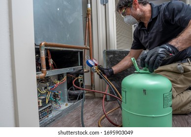 HVAC Contractor Wearing A Mask And Safety Glasses While Charging A Heat Pump Air Conditioner