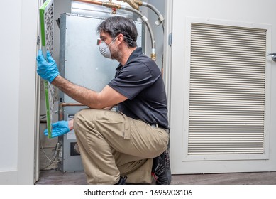 Hvac Contractor Wearing A Medical Mask Inspecting An Air Filter On A Heat Pump