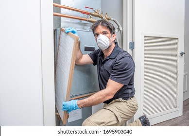 HVAC Contractror Wearing A Medical Face Mask, Replacing A Air Filter Inside A Home