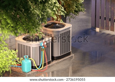 HVAC installation, Climate control services. Outdoor air conditioning units connected to refrigerant gauges and gas cylinder for cooling system maintenance and energy efficiency, 