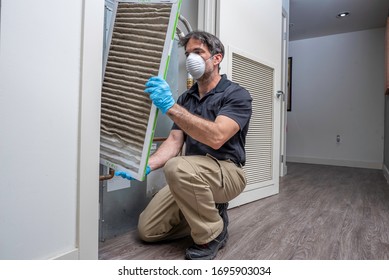 HVac Maintenance Technician Removing A Diry Air Filter From A Heat Pump