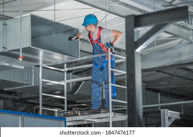 HVAC Professional Technician Worker Looking Inside Newly Built Metal Air Duct Inside Commercial Warehouse Building.