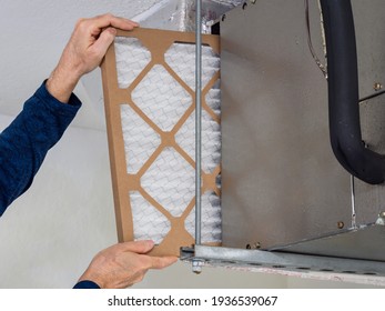 HVAC service technician changing dirty indoor air filter in residential heating and air conditioning system. Home air duct ventilation system maintenance for clean air.